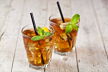 Image showing Traditional iced tea with lemon, mint leaves and ice cubes in tw