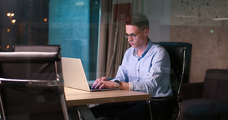 Image showing man working on laptop in dark office