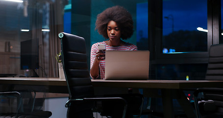 Image showing black businesswoman using a laptop in night startup office