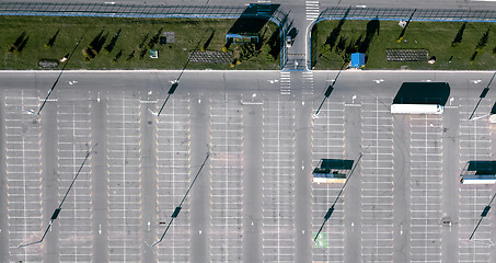 Image showing Aerial view of a drone with a truck in the parking lot next to a green lawn and the reflection of shadows from street lamps on a sunny day.