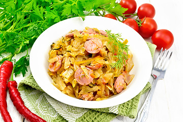 Image showing Cabbage stew with sausages in white plate on napkin