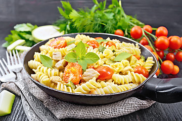 Image showing Fusilli with chicken and tomatoes in pan on dark board