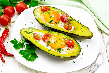 Image showing Scrambled eggs with tomatoes in avocado on white wooden board