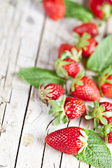 Image showing Fresh red strawberries and mint leaves on rustic wooden backgrou