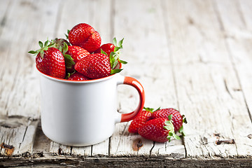 Image showing Organic red strawberries in white ceramic cup on rustic wooden b