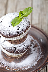 Image showing Fresh chocolate dark muffins with sugar powder and mint leaf on 