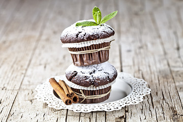 Image showing Chocolate dark muffins with sugar powder, cinnamon sticks and mi