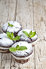 Image showing Fresh chocolate dark muffins with sugar powder and mint leaf on 