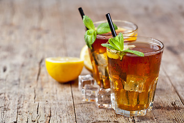 Image showing Traditional iced tea with lemon, mint leaves and ice cubes in tw