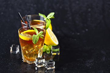 Image showing Traditional iced tea with lemon, mint leaves and ice cubes in tw