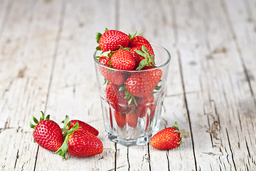 Image showing Fresh red strawberries in glass on rustic wooden background.