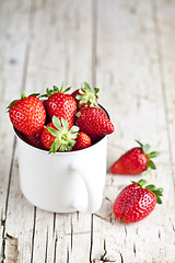 Image showing Organic red strawberries in white ceramic cup on rustic wooden b