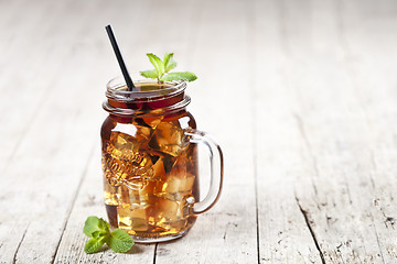 Image showing Traditional iced tea with lemon, mint leaves and ice cubes in gl