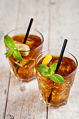 Image showing Traditional iced tea with lemon, mint leaves and ice cubes in tw