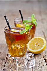 Image showing Traditional iced tea with lemon, mint leaves and ice cubes in tw