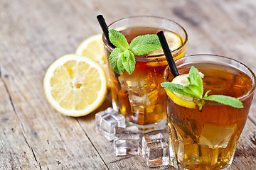 Image showing Traditional iced tea with lemon, mint leaves and ice cubes in tw