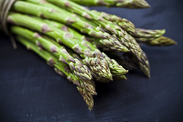 Image showing Bunch of fresh raw garden asparagus closeup on black board backg