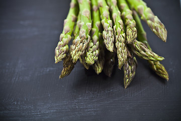 Image showing Bunch of fresh raw garden asparagus closeup on black board backg