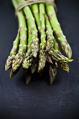 Image showing Bunch of fresh raw garden asparagus closeup on black board backg