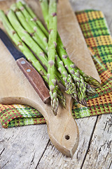 Image showing Fresh raw garden asparagus and knife closeup on cutting board on