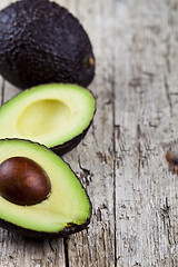 Image showing Avocado on old wooden table background. Fresh avocado halves on 