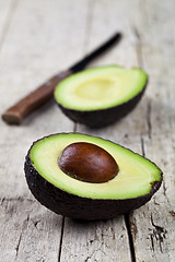 Image showing Avocado and knife on old wooden table background. Fresh avocado 