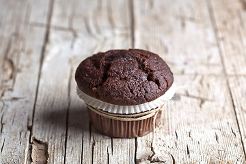 Image showing Fresh single dark chocolate muffin on rustic wooden table.