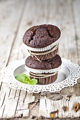 Image showing Two fresh dark chocolate muffins with mint leaves on white plate