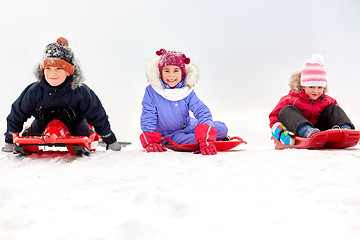 Image showing happy little kids sliding down on sleds in winter