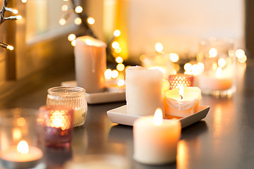Image showing candles burning on window sill with garland lights