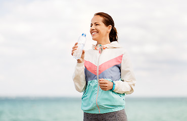 Image showing woman drinking water after exercising at seaside