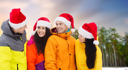 Image showing friends in santa hats and ski suits on christmas