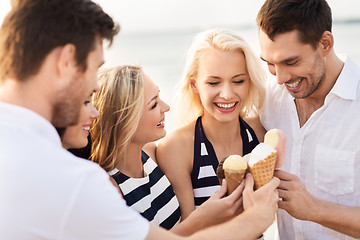 Image showing happy friends eating ice cream on beach