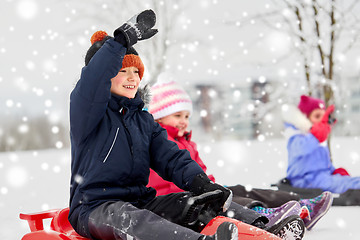 Image showing happy kids sliding on sleds in winter