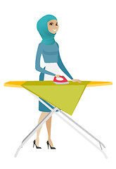 Image showing Muslim maid ironing clothes on ironing board.