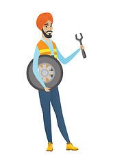 Image showing Young hindu mechanic with tyre and spanner.