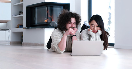 Image showing young multiethnic couple using a laptop on the floor