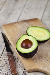 Image showing Avocado and knife on cutting board on old wooden table backgroun