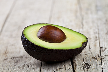 Image showing Fresh organic avocado half on old wooden table background.