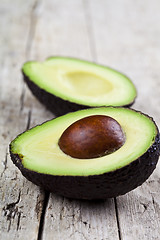 Image showing Fresh organic avocado halves on old wooden table background. Fre