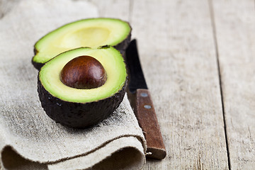 Image showing Avocado and knife on linen napkin old wooden table background. F