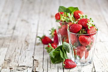 Image showing Red fresh strawberries in two glasses and mint leaves on rustic 