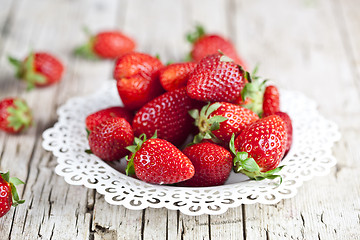 Image showing Fresh red strawberries on white plate on rustic wooden backgroun