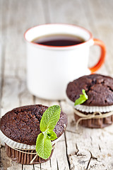 Image showing Fresh dark chocolate muffins with mint leaves and cup of tea on 