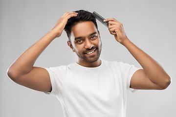 Image showing happy indian man brushing hair with comb