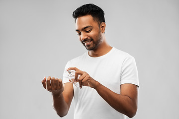 Image showing happy indian man with perfume over gray background