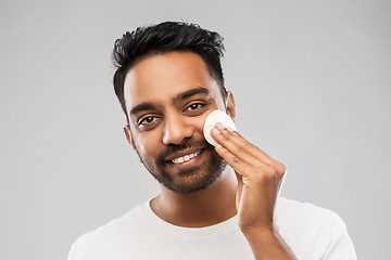 Image showing smiling indian man cleaning face with cotton pad