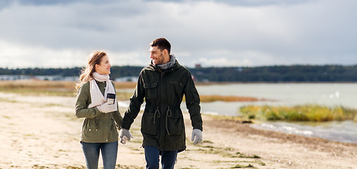 Image showing couple with tumbler walking along autumn beach