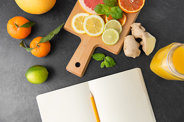 Image showing close up of fruits and notebook on slate table top