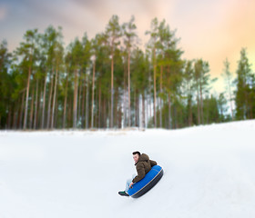 Image showing happy young man sliding down hill on snow tube